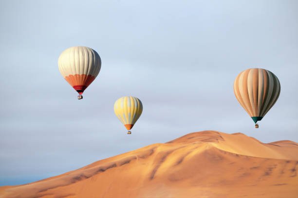 Colored hot air balloons flying over the sand dunes at sunset. Africa, Namibia. Beauty world.